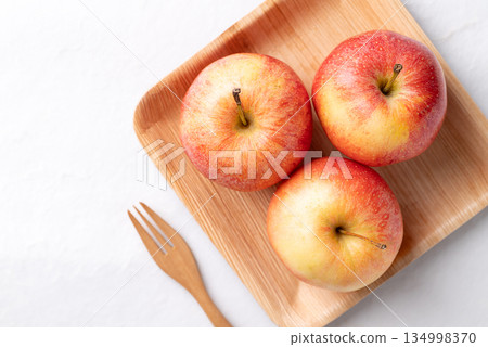 Red apple fruit (Gala apple) in natural plate with wooden fork on white background Red apple fruit (Gala apple) in natural plate with wooden fork on white background 134998370