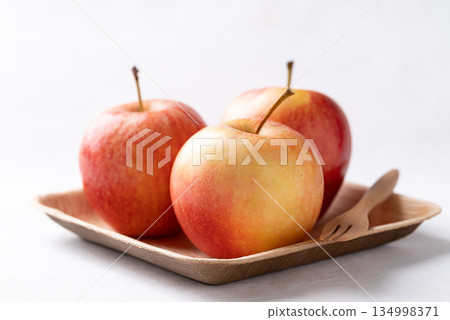 Red apple fruit (Gala apple) in natural plate with wooden fork on white background Red apple fruit (Gala apple) in natural plate with wooden fork on white background 134998371