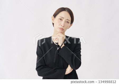 Thinking woman in mourning clothes looking at camera white background 134998812