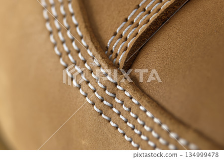 Close-up of tan suede material with detailed white stitching and texture Close-up of tan suede material with detailed white stitching and texture 134999478
