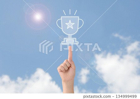 Child's hand pointing at a trophy towards the blue sky Child's hand pointing at a trophy towards the blue sky 134999499