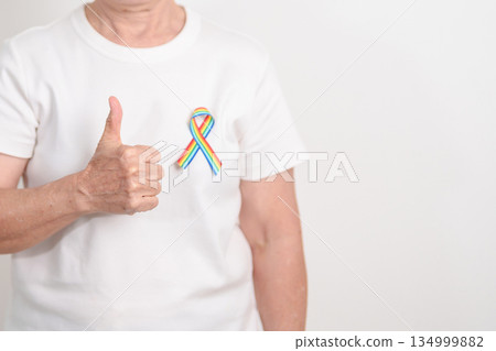 Elderly with LGBTQ Rainbow ribbon for concept of June Pride month, April Autism Awareness, All cancer Awareness, February World Cancer day, October World Hospice and Palliative care day and Survivor 134999882