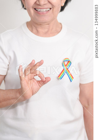 Elderly with LGBTQ Rainbow ribbon for concept of June Pride month, April Autism Awareness, All cancer Awareness, February World Cancer day, October World Hospice and Palliative care day and Survivor 134999883