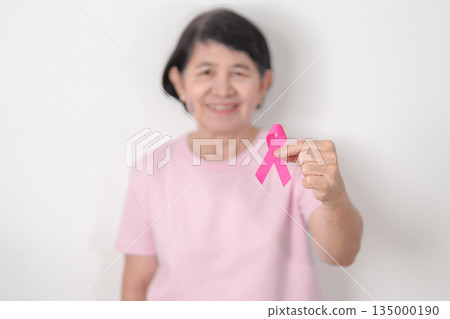 Elderly woman with pink Ribbon for Pink October Breast Cancer Awareness month, May Women Health, February World cancer day, support people life and illness. National cancer survivors month Elderly woman with pink Ribbon for Pink October Breast Cancer Awareness month, May Women Health, February World cancer day, support people life and illness. National cancer survivors month 135000190