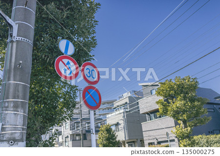 Multiple traffic control signs installed on a road in a residential area 135000275