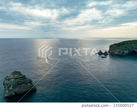 Drone shot of the waters off Hirizohama at dusk. A fishing boat is sailing on a sunset cruise. Hirizohama, Nakagi, Minamiizu Town 135000527