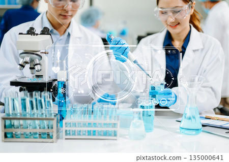 scientists in lab coats conducting research, handling glassware, and working with chemicals in a modern, high tech laboratory. 135000641