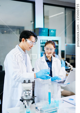 Scientists collaborating in a bright modern lab with blue liquids and microscopes, symbolizing teamwork, biotechnology, chemistry, and medical innovation. Scientists collaborating in a bright modern lab with blue liquids and microscopes, symbolizing teamwork, biotechnology, chemistry, and medical innovation. 135000735