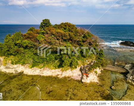 Ryugujima Island in Shimoda, Izu, and the red torii gate of Shirashima Shrine. Drone shot from Ogasaki Wing. Blue sea, white waves, and green forest. 135000868