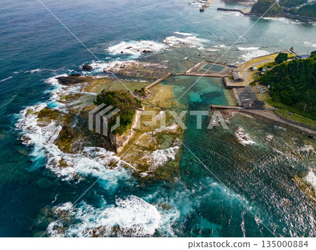 Ryugujima Island in Shimoda, Izu, and the red torii gate of Shirashima Shrine. Drone shot from Ogasaki Wing. Blue sea, white waves, and green forest. 135000884