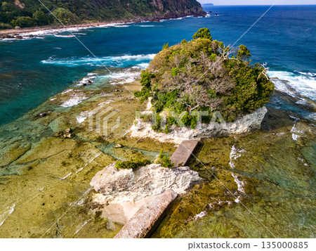 Ryugujima Island in Shimoda, Izu, and the red torii gate of Shirashima Shrine. Drone shot from Ogasaki Wing. Blue sea, white waves, and green forest. Ryugujima Island in Shimoda, Izu, and the red torii gate of Shirashima Shrine. Drone shot from Ogasaki Wing. Blue sea, white waves, and green forest. 135000885