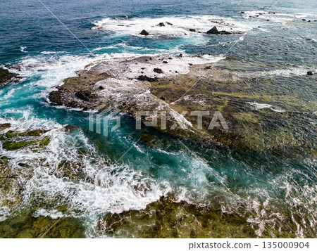 Ryugujima Island in Shimoda, Izu, and the red torii gate of Shirashima Shrine. Drone shot from Ogasaki Wing. Blue sea, white waves, and green forest. 135000904