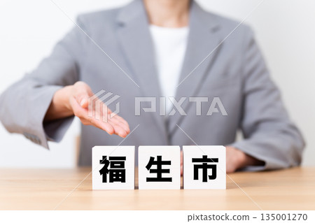 Fussa city block and a middle-aged female business woman wearing a suit Fussa city block and a middle-aged female business woman wearing a suit 135001270