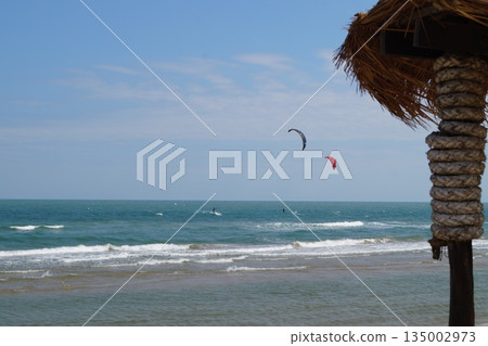 A cozy place to relax on the beach.A beautiful place to relax and unwind on the beach by the sea. A beautiful bamboo and straw bar counter sits against a backdrop of blue sky and turquoise sea. 135002973