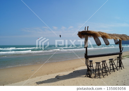 A beautiful place to relax and unwind on the beach by the sea. A beautiful bamboo and straw bar counter sits against a backdrop of blue sky  135003056