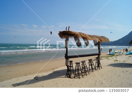 A cozy place to relax on the beach.A beautiful place to relax and unwind on the beach by the sea. A beautiful bamboo and straw bar counter sits against a backdrop of blue sky and turquoise sea. 135003057