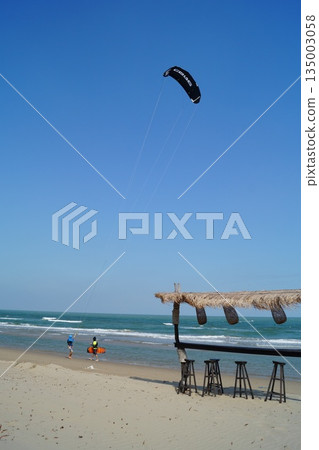 A beautiful place to relax and unwind on the beach by the sea. A beautiful bamboo and straw bar counter sits against a backdrop of blue sky and turquoise sea. 135003058