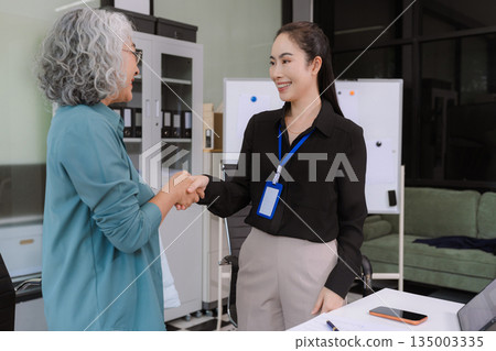 Asian businesswomen shaking hands at startup office meeting. 135003335