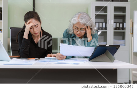 Stressed asian mature business woman working in the office. 135003345