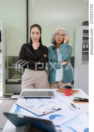 Business team analyzing documents, graphs, and data with a laptop, tablet, and smartphone. Collaboration, strategy, and success. Business team analyzing documents, graphs, and data with a laptop, tablet, and smartphone. Collaboration, strategy, and success. 135003358