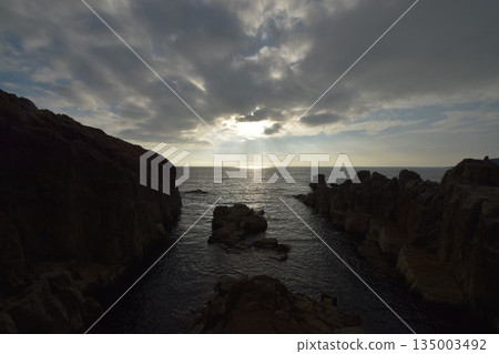 The silhouette of the columnar jointed cliffs and dramatic sky at Tojinbo, a scenic spot in Fukui Prefecture 135003492