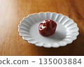 盤子上放著一顆醃梅子，背景是木紋。 135003884