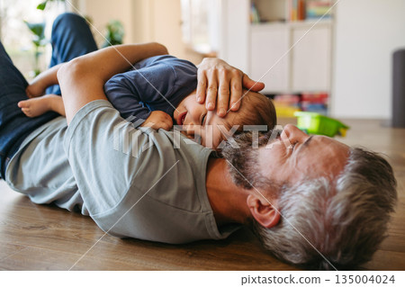 Father playing with little son with toys on the floor. 135004024
