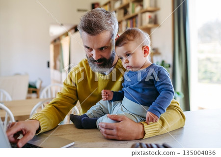 Dad working from homeoffice and taking care of toddler. 135004036