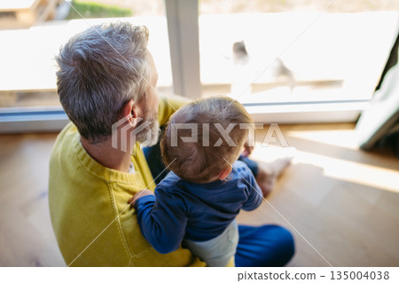 Father with little toddler son looking out of window. 135004038