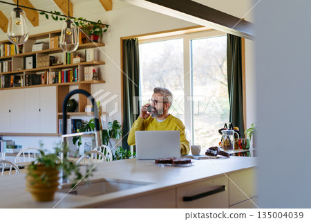 Man working from home while on phone call. Man working from home while on phone call. 135004039