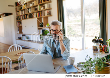 Man working from home while on phone call. 135004040
