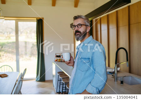 Middle aged man drinking coffee in kitchen. Middle aged man drinking coffee in kitchen. 135004041