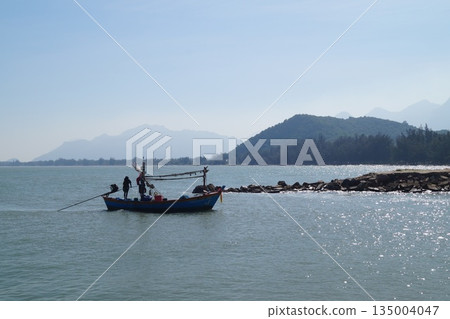 A small, wooden, colorful fisherman's boat returning from fishing to the village.Wooden fisherman's boat at sea. 135004047