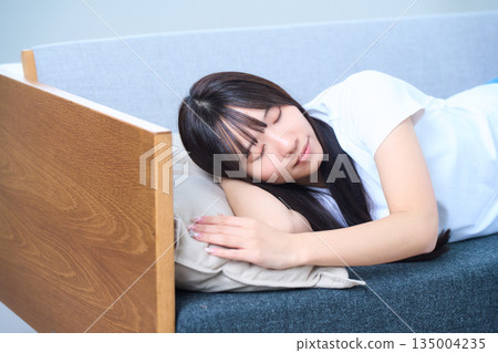 一位年輕的日本女子在沙發上舒適地小憩。 一位年輕的日本女子在沙發上舒適地小憩。 135004235