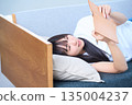 A young Japanese woman looking at her notebook on the sofa 135004237