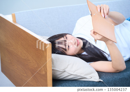 A young Japanese woman looking at her notebook on the sofa 135004237