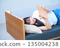 A young Japanese woman looking at her notebook on the sofa 135004238