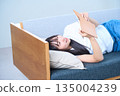 A young Japanese woman looking at her notebook on the sofa 135004239