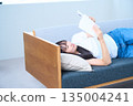 Young Japanese woman reading a book on the sofa 135004241
