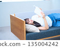 Young Japanese woman reading a book on the sofa 135004242