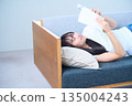Young Japanese woman reading a book on the sofa 135004243