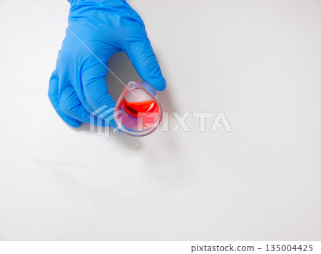 Gloved Hand Holding Red Sample Cup, Clinical Surface, Sterile Technique, Diagnostic Testing, Reflective Gloved Hand Holding Red Sample Cup, Clinical Surface, Sterile Technique, Diagnostic Testing, Reflective 135004425