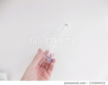 Bare Hand Holding Glass Pipette Over White Background, Delicate Transfer Of Clear Sample Into Tube, Precise Bare Hand Holding Glass Pipette Over White Background, Delicate Transfer Of Clear Sample Into Tube, Precise 135004432