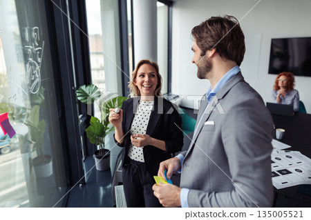 Two colleagus reviewing project layout during meeting. 135005521