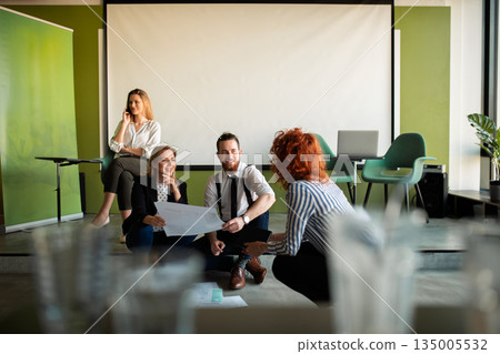 Team brainstorming on the office floor, discussing marketing strategy. 135005532