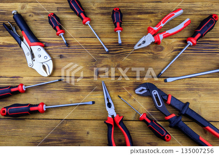 Set of different pliers and screwdrivers on wooden background. Top view, copy space Set of different pliers and screwdrivers on wooden background. Top view, copy space 135007256