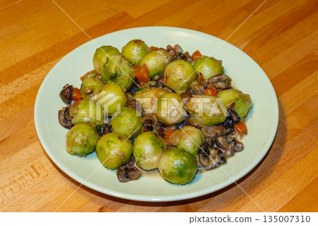 Brussels sprouts roasted with mushrooms and carrot on wooden table 135007310