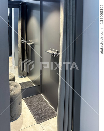 Modern fitting room with mirror, gray curtain, and stool. Modern fitting room with mirror, gray curtain, and stool. 135008393