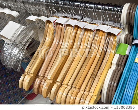 Wood and plastic hangers displayed on a rack. Wood and plastic hangers displayed on a rack. 135008396