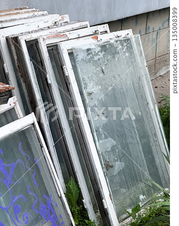 Stack of old windows with peeling frames for recycling or repurposing. Stack of old windows with peeling frames for recycling or repurposing. 135008399